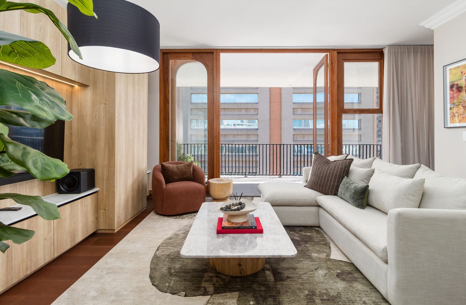 Living room opening through arched timber doors to a city balcony