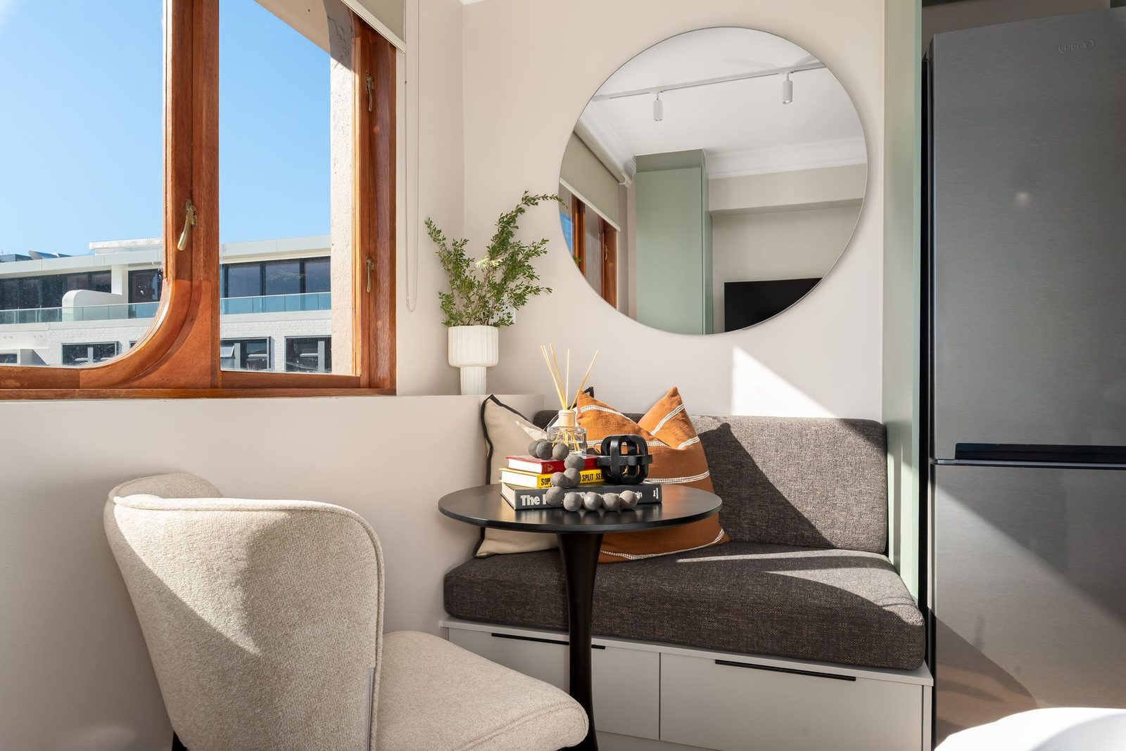 Window nook with a built-in bench, round mirror and curved timber window