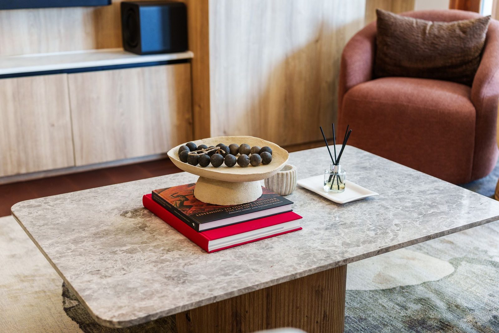 Marble coffee table styled with a clay bowl, black beads and art books