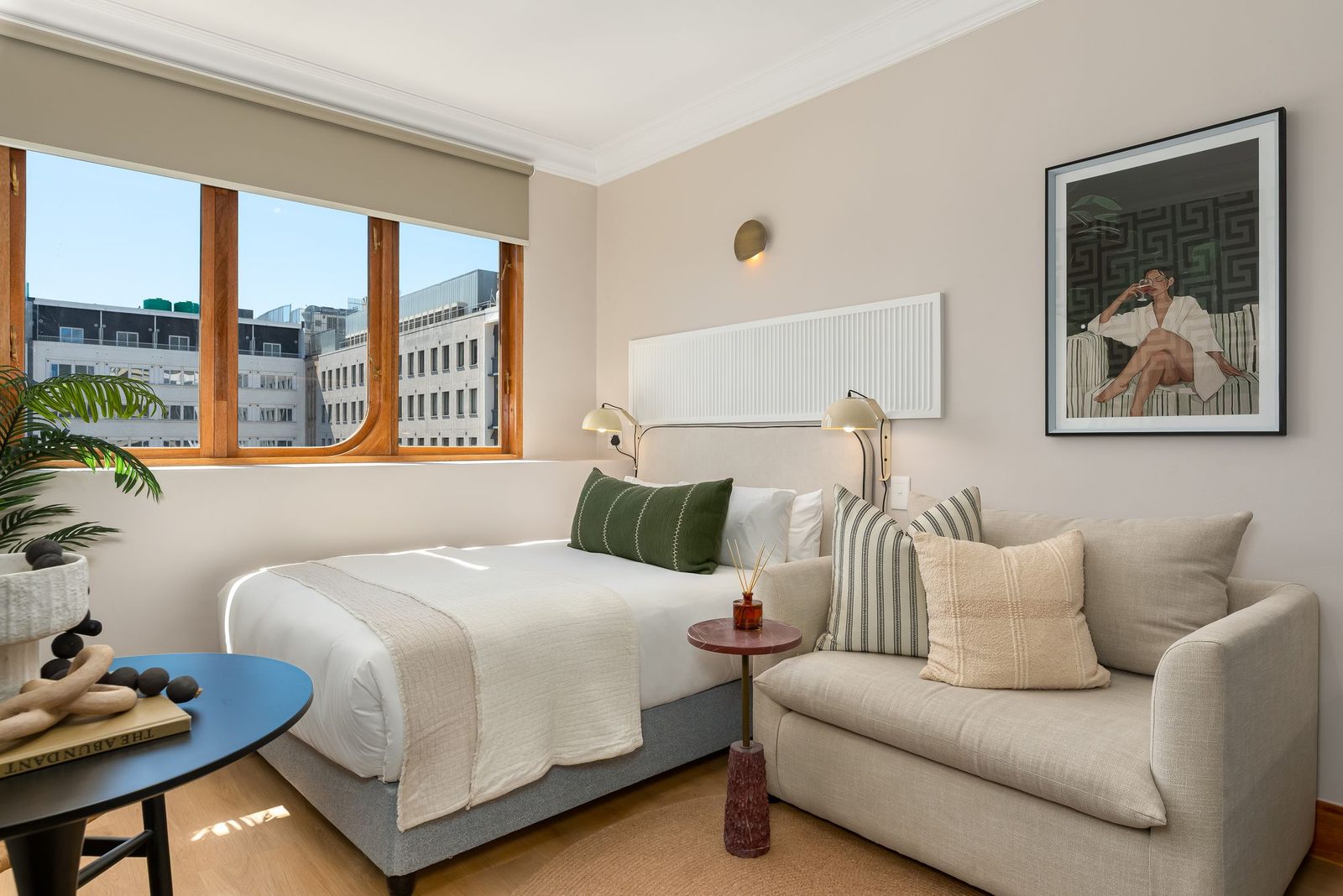 Studio with a linen sofa, a fluted headboard panel and a curved timber window