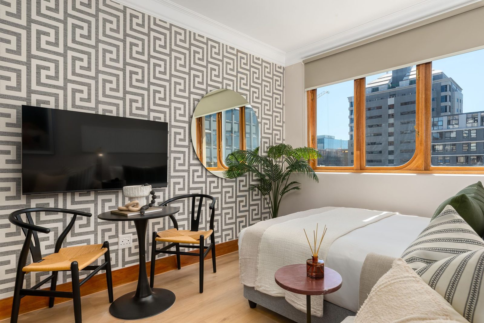 Studio with a Greek key wallpaper, wishbone chairs and a round mirror