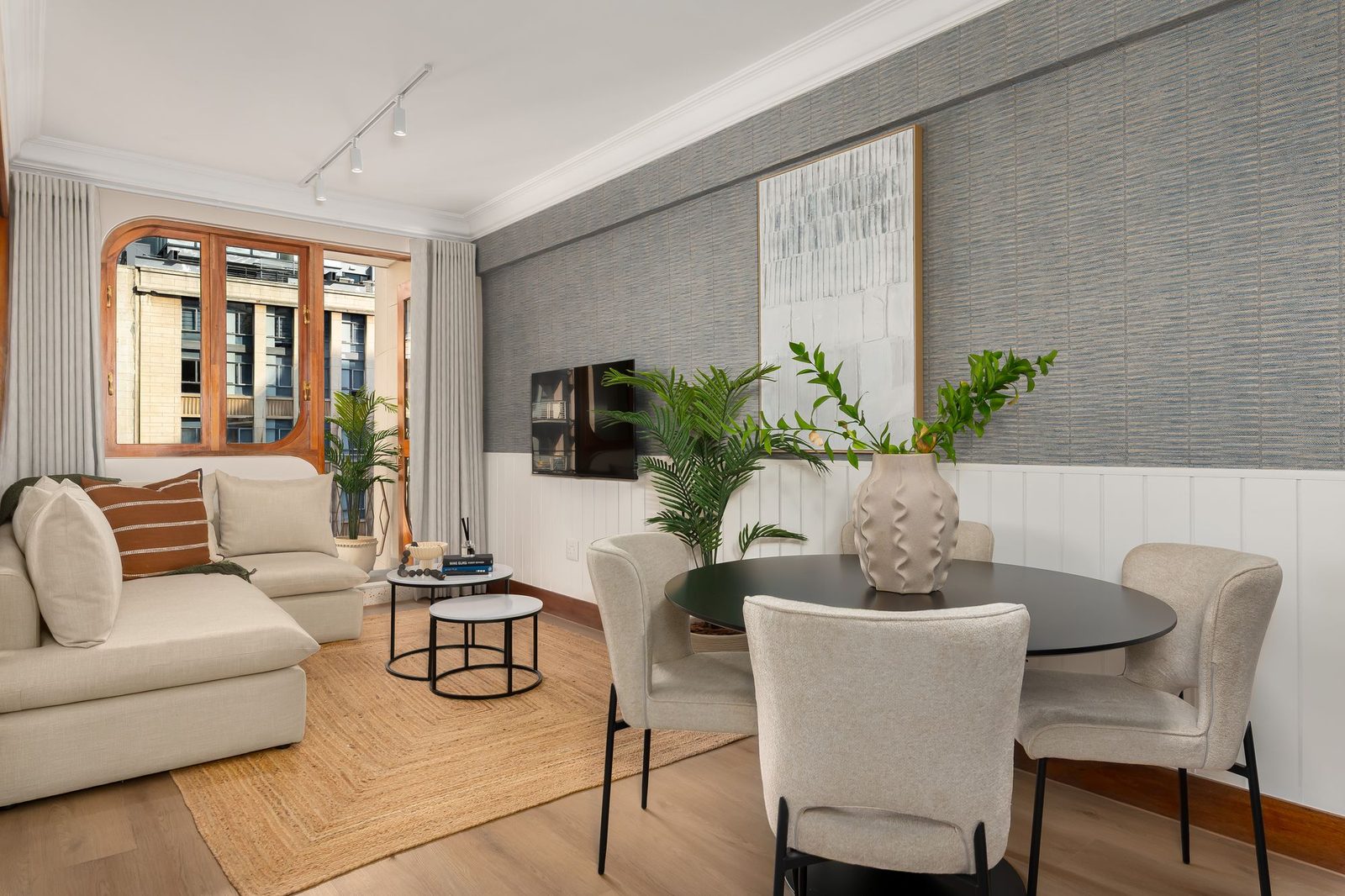 Living and dining room with a grasscloth wall, panelling and a round black table