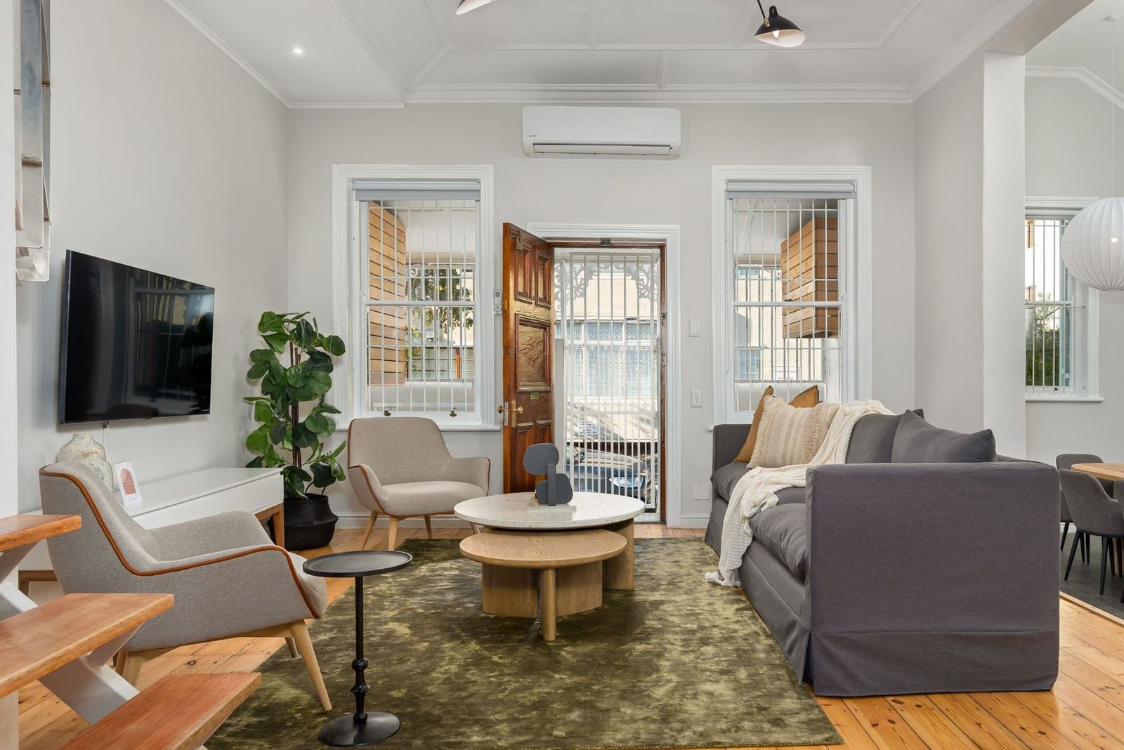 Cottage living room with a terrazzo coffee table, green rug and the original front door