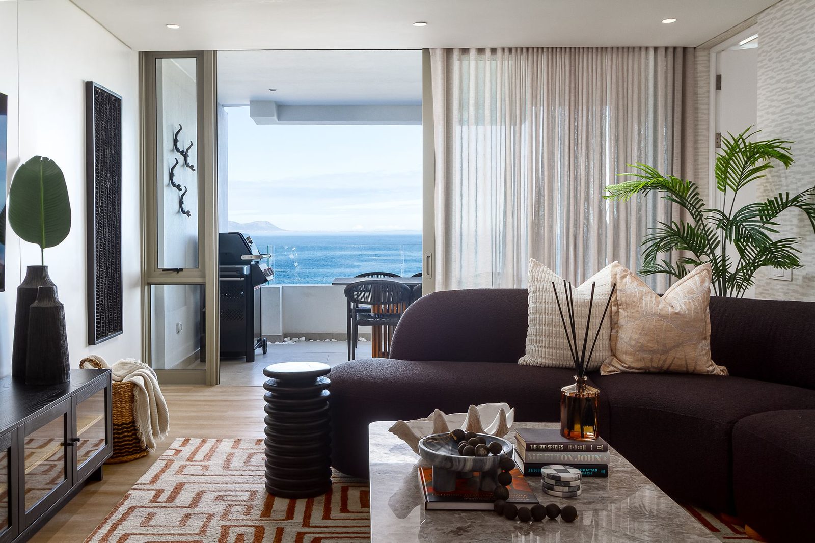 The Mira: living room with a dark boucle sofa and a view of the sea