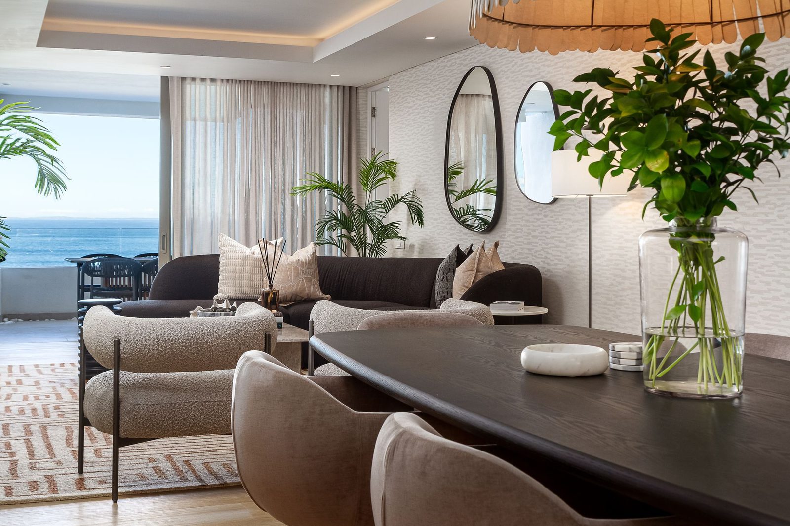 Dining table in dark oak with velvet chairs, boucle armchairs and pebble-shaped mirrors