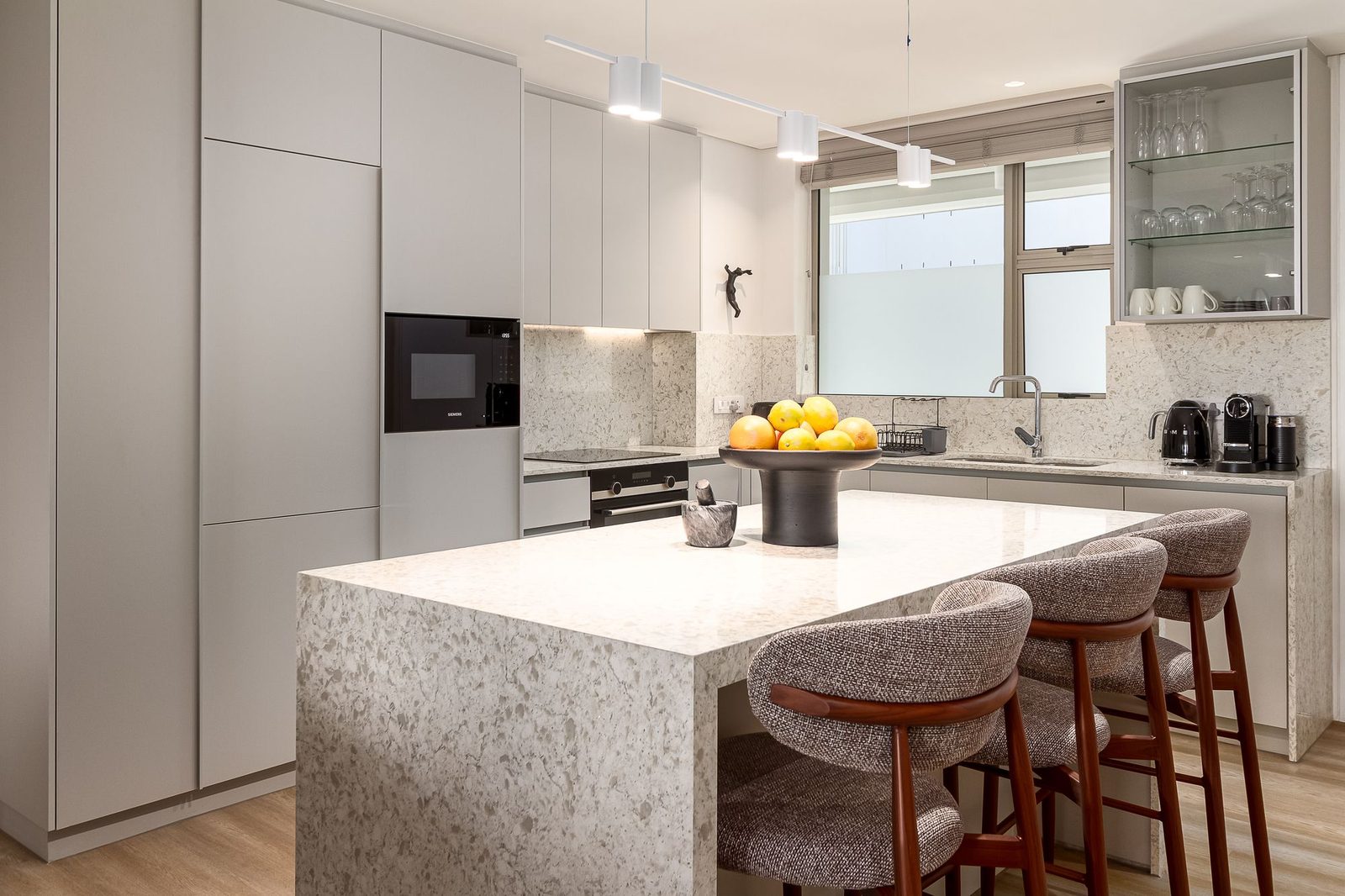 Kitchen with a terrazzo waterfall island and upholstered bar stools