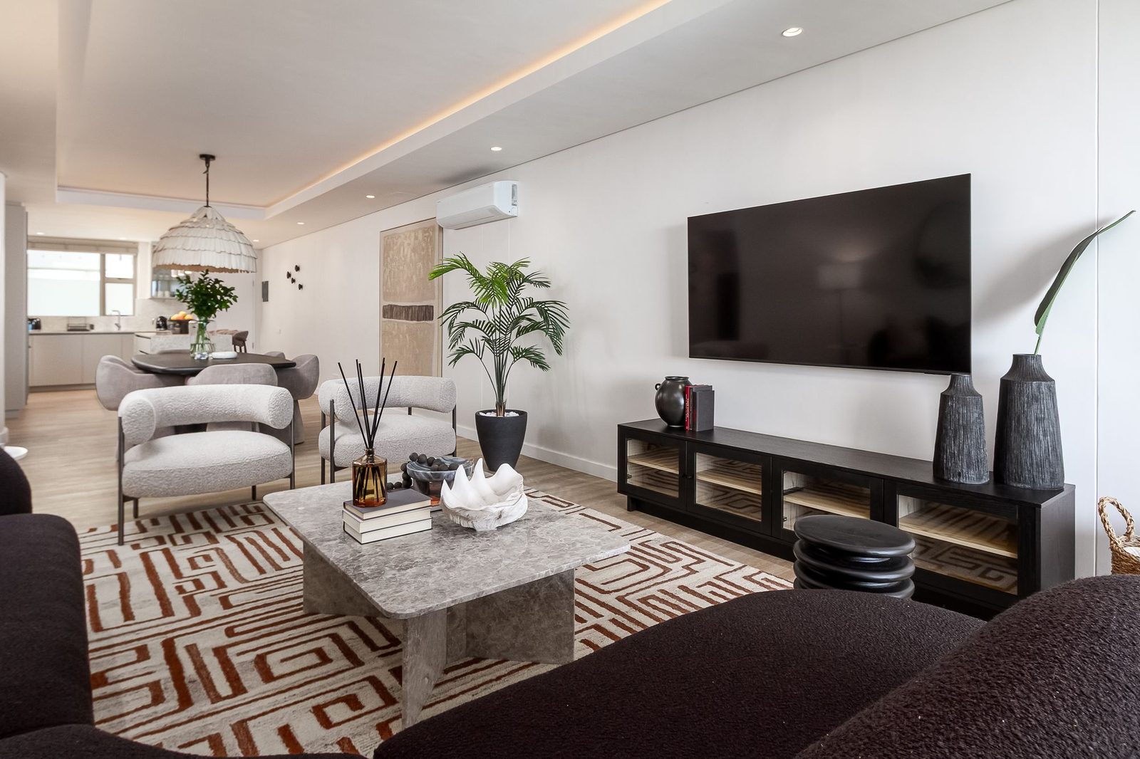 Living room with boucle armchairs, a marble coffee table and a black media unit