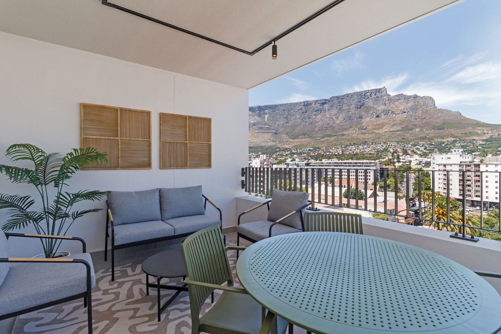 Covered balcony with outdoor seating and a green dining table facing Table Mountain