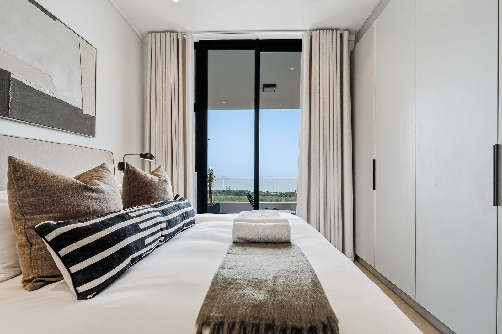 Bedroom with striped cushions, linen curtains and a sea view